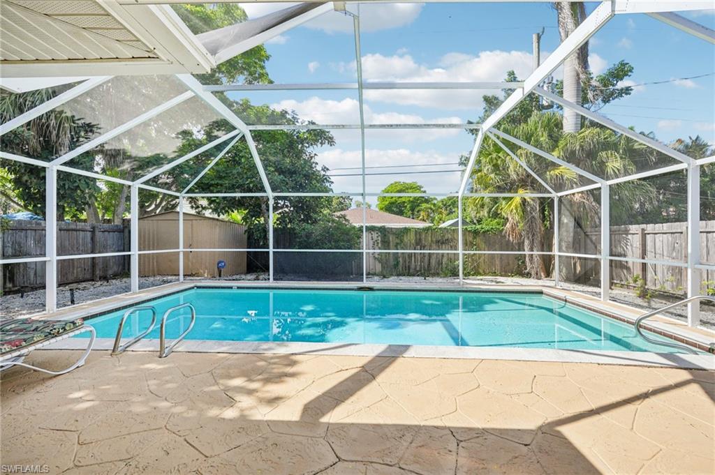View of swimming pool featuring a fenced backyard, a sunroom, a lanai, and patio surround