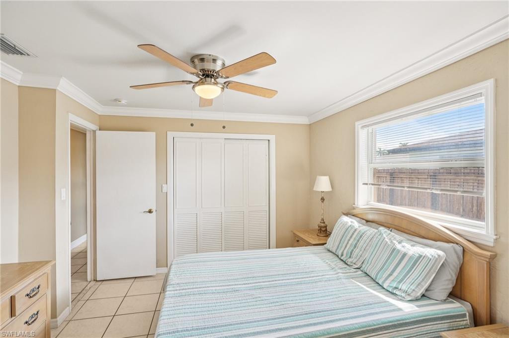 Bedroom with crown molding, ceiling fan, light tile patterned floors, and a closet