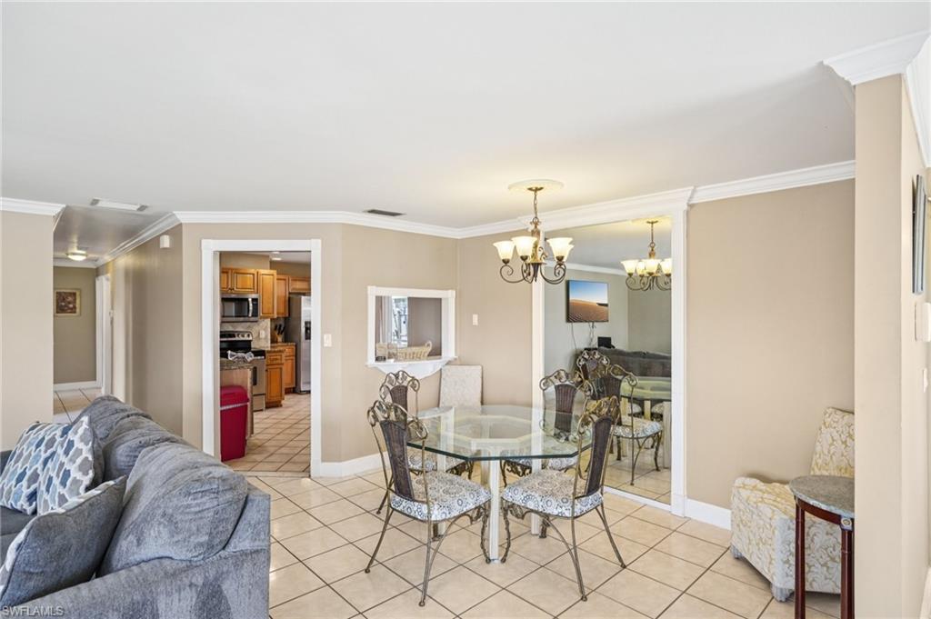 Dining space with ornamental molding, a chandelier, and light tile patterned flooring