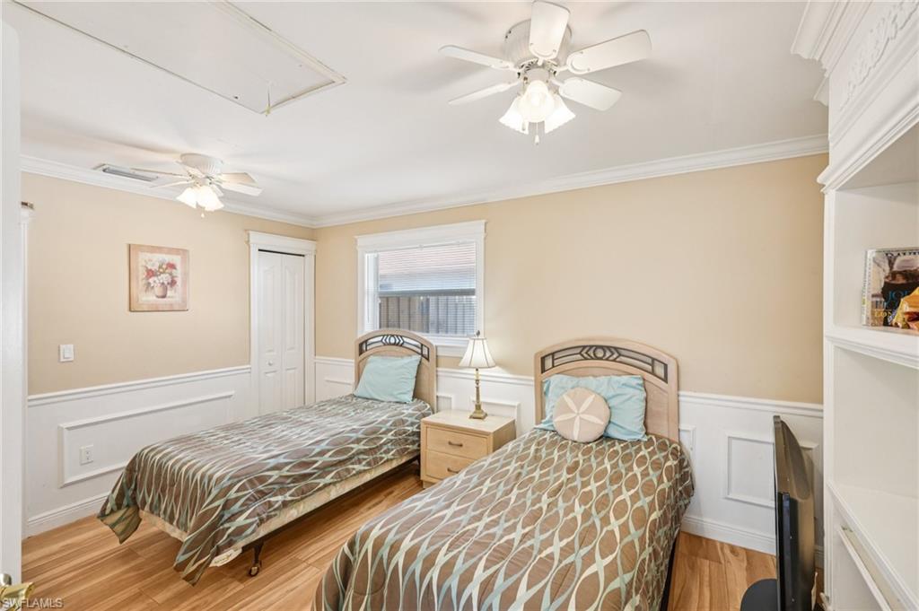 Bedroom with a wainscoted wall, a closet, a ceiling fan, a decorative wall, and light wood-style floors