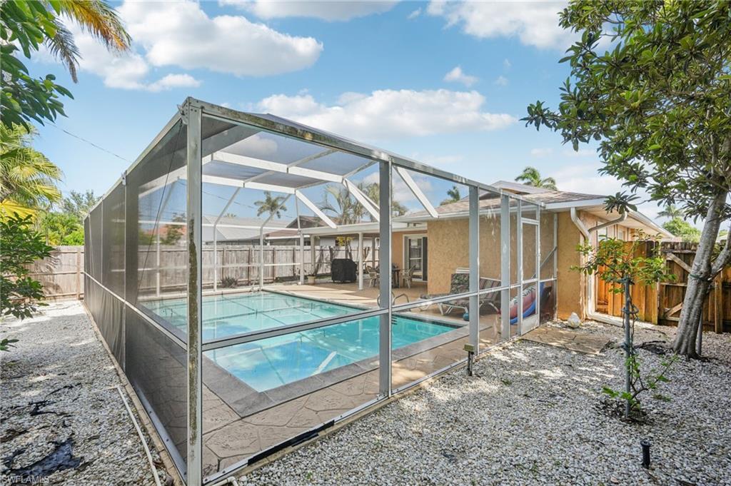 View of swimming pool featuring a sunroom, a lanai, a fenced backyard, and patio surround