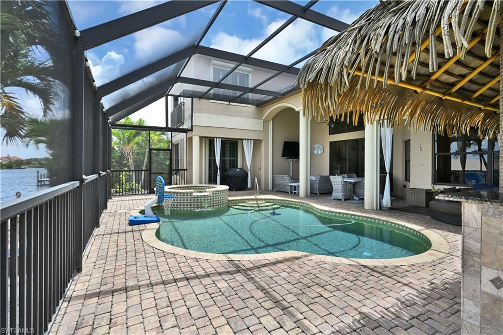 Screened outdoor living area featuring a freeform swimming pool with integrated spa