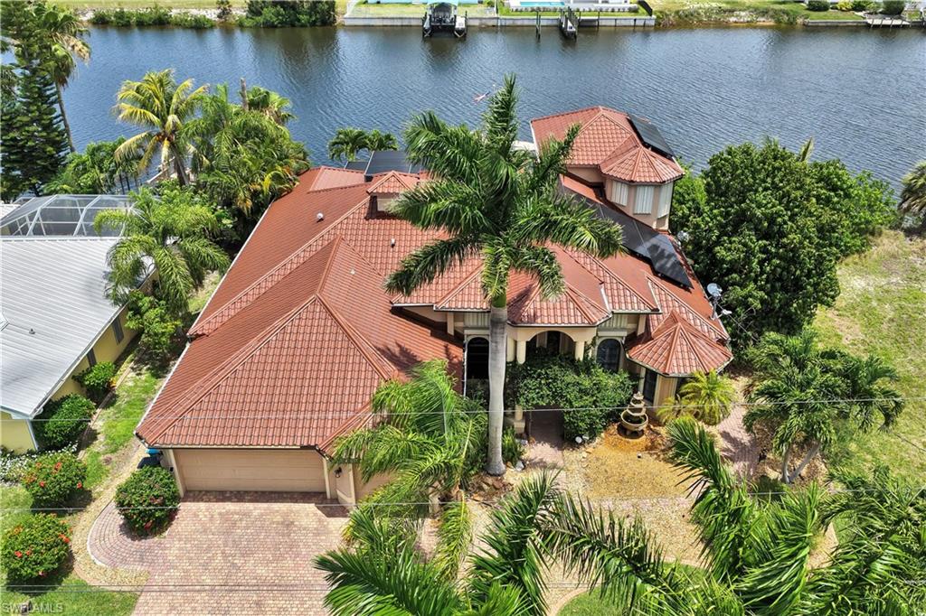 Waterfront residence featuring a red tile roof, an integrated two-car garage, and a paver driveway