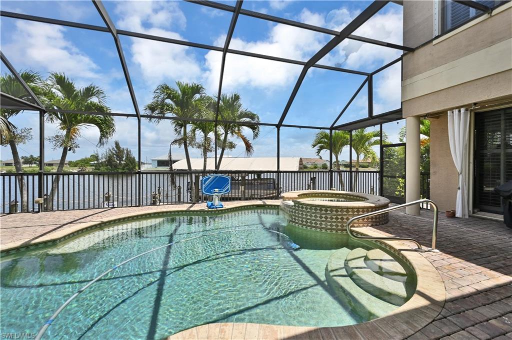 Screened lanai featuring a swimming pool, integrated hot tub with mosaic tile, and a paver deck