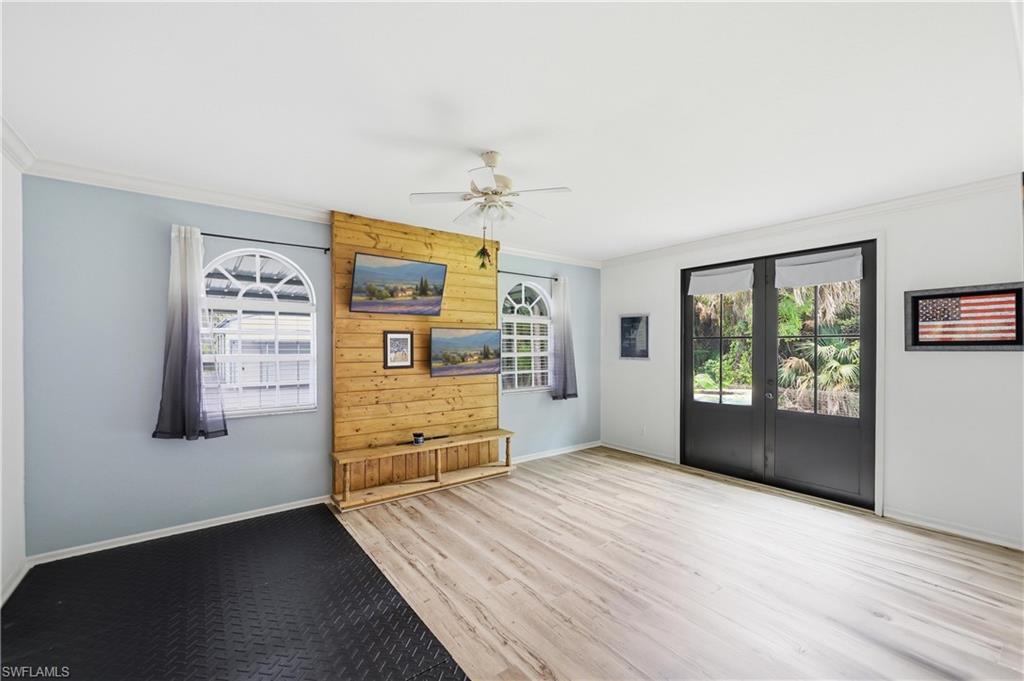 Media room features luxury vinyl flooring, custom accent wall, and French doors opening to the backyard.