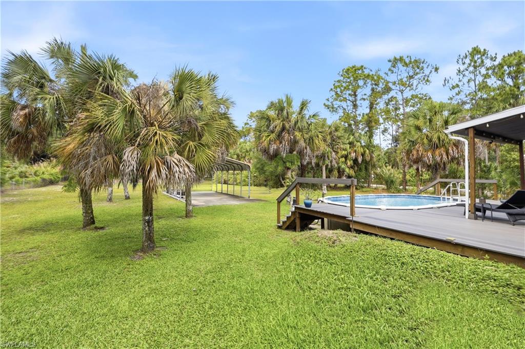 Backyard features an above-ground pool with PVC deck, open green space, and mature palms.
