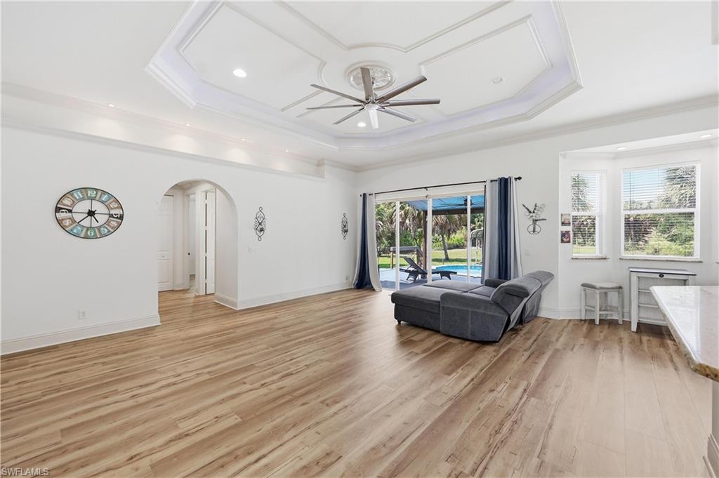 Expansive great room with decorative tray ceiling, recessed lighting, and views toward the outdoor living area.