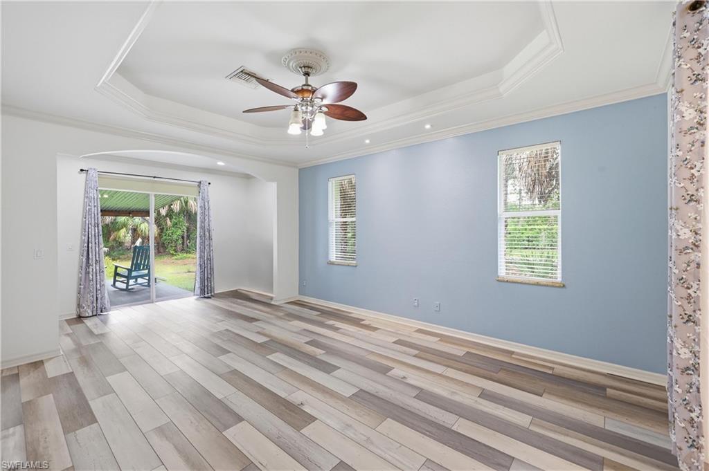Primary suite with tray ceiling detail, large windows, and sliding glass door access to the covered outdoor area.