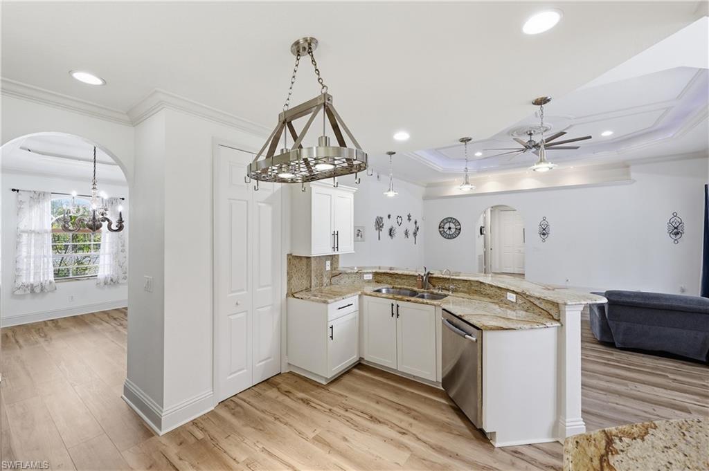 Kitchen with granite countertops, white cabinetry, pendant lighting, and an open connection to the living area.