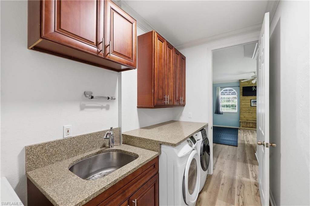Laundry room includes built-in cabinetry, a utility sink, generous counter space, and washer and dryer.