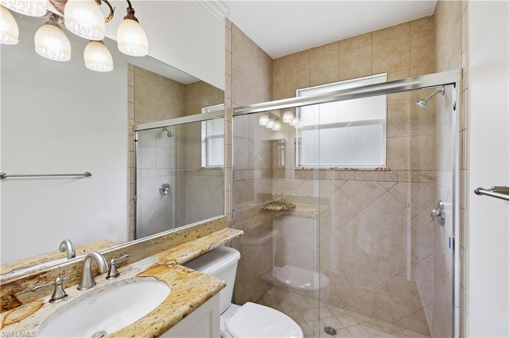 Full bathroom with granite vanity top, tiled walk-in shower, and natural light.