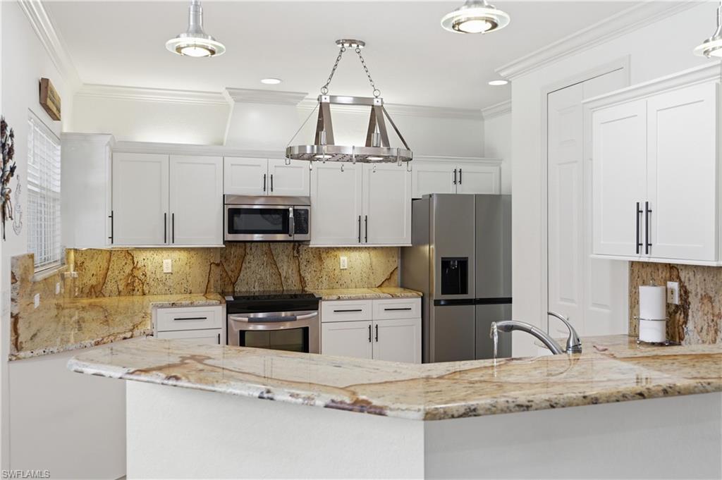 Spacious kitchen with white cabinetry, granite countertops, stainless steel appliances, and a breakfast bar.