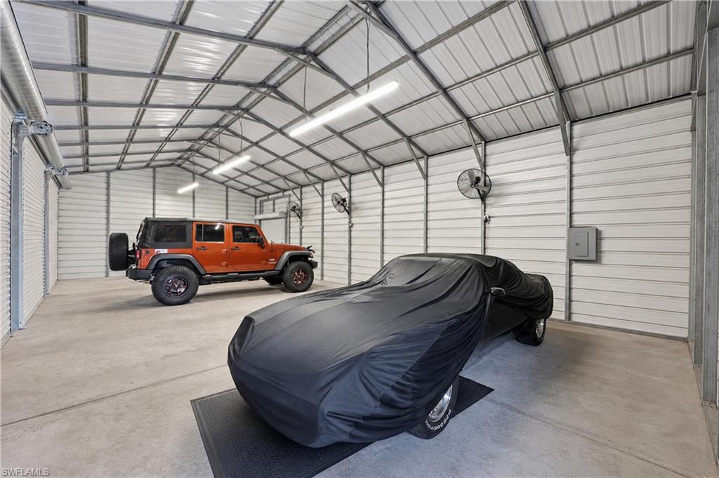 Spacious steel garage offers multiple vehicle bays, high ceilings, concrete floors, and overhead roll-up doors.