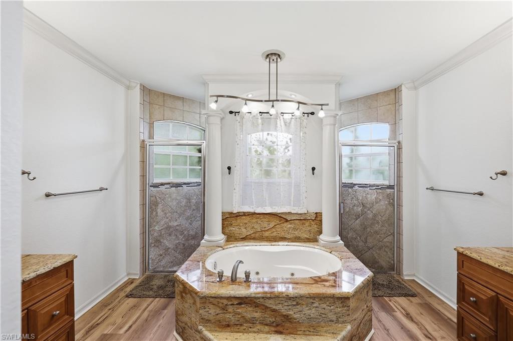 Spacious primary bathroom features a jetted soaking tub, dual walk-in showers, and dual vanities with granite countertops.