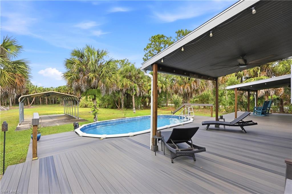 Covered outdoor living space provides shaded seating with views of the pool and landscaped grounds.