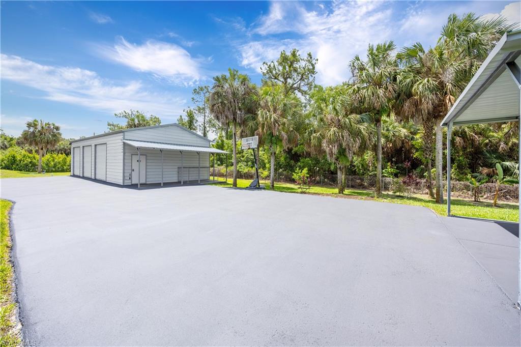 Expansive paved driveway leads to the detached steel garage with multiple bays and additional covered parking.