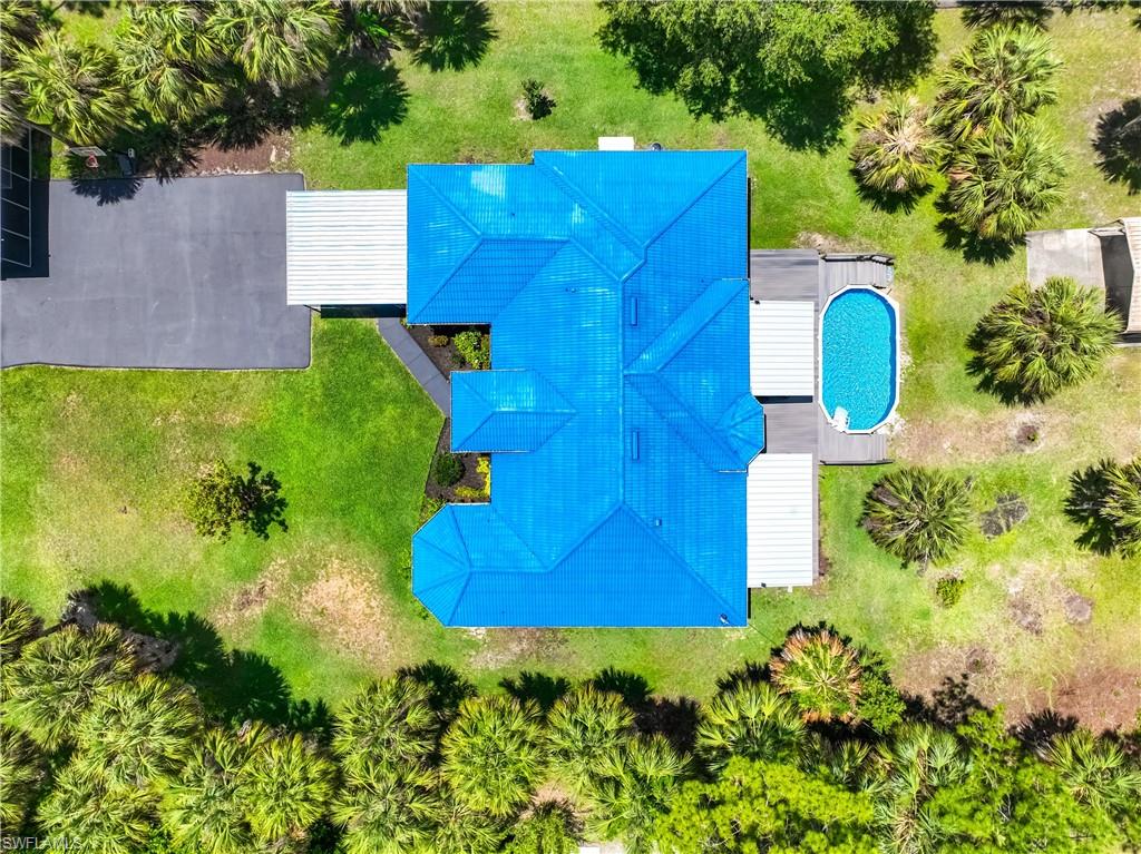 Overhead view highlights the home's layout, metal roof, pool, and outdoor living areas.