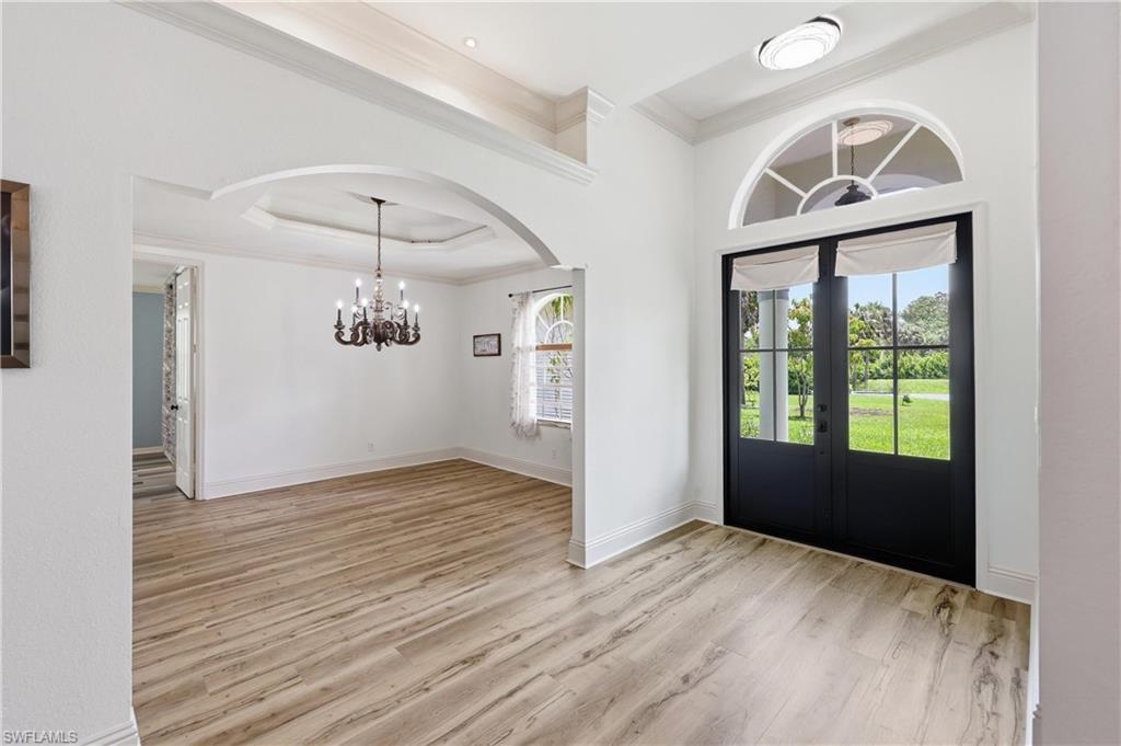 Welcoming foyer opening to a formal dining area with arched entryways and decorative lighting.