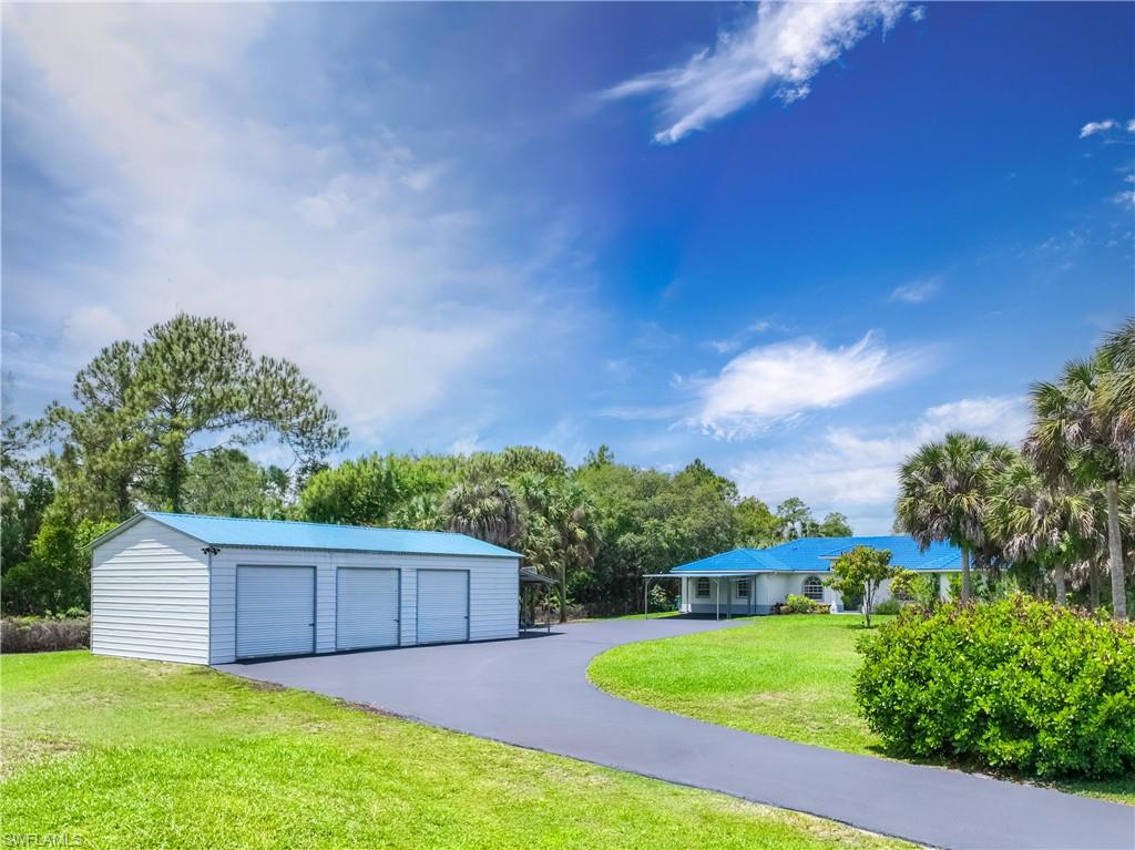 Circular driveway connects the Naples Florida home to the detached steel garage and covered carport.