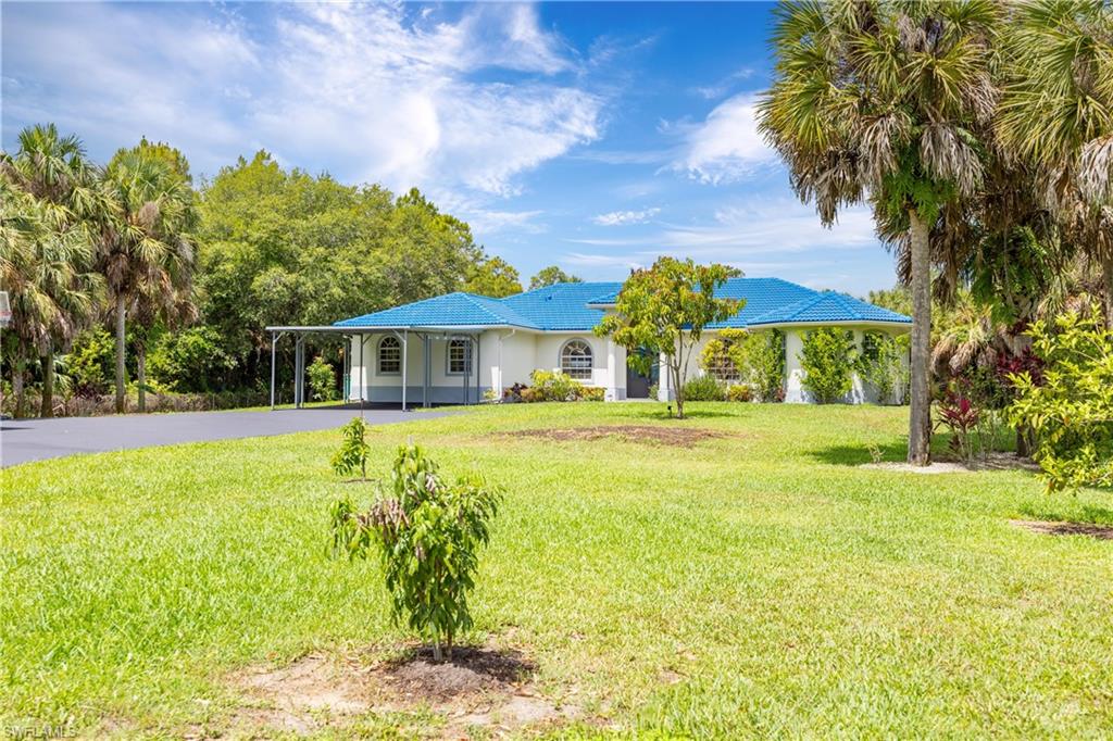 Spacious front lawn is enhanced by mature palms and established landscaping on the 2.81-acre property.