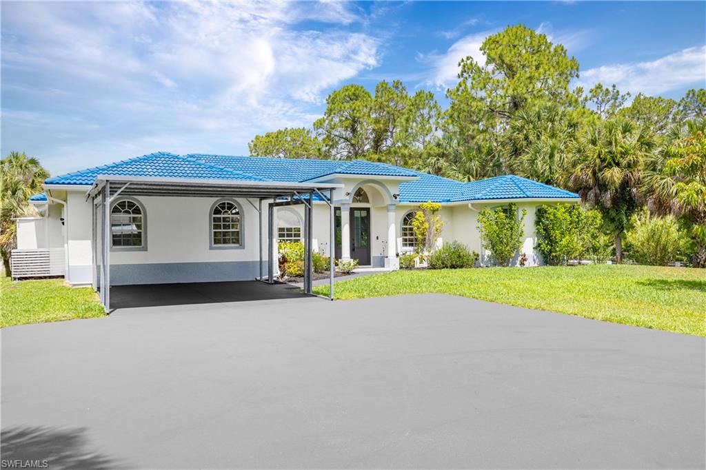 Covered carport and wide driveway provide convenient parking alongside the Naples Florida home.