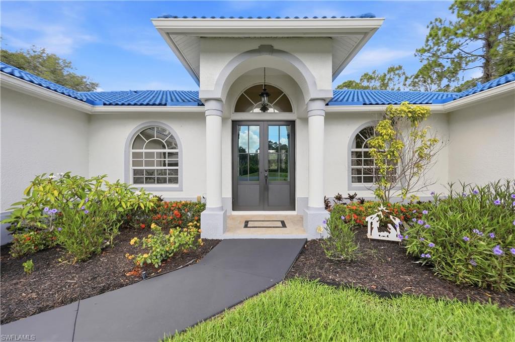 Covered front entry with column accents, double doors, and landscaped walkway.
