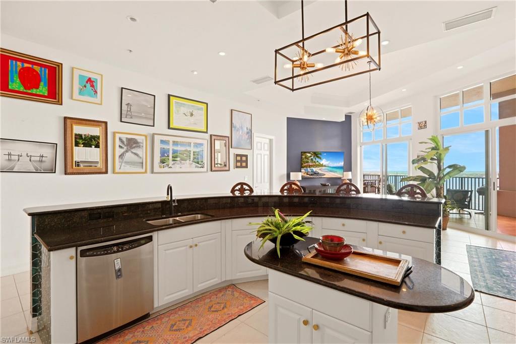 Kitchen with dark stone counters, white cabinetry, stainless steel dishwasher, and light tile patterned floors