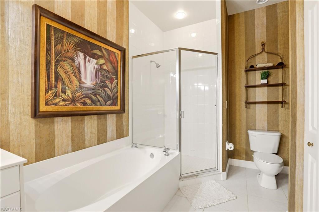 Bathroom with wallpapered walls, a garden tub, a shower stall, vanity, and light tile patterned floors