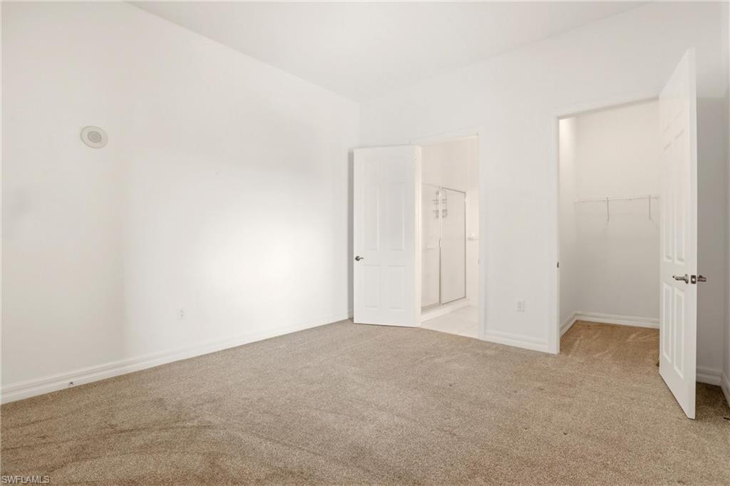 Unfurnished bedroom featuring a spacious closet, carpet, and connected bathroom