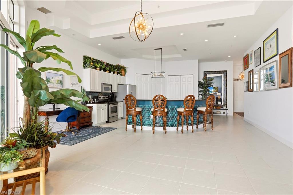Dining space with light tile patterned floors, suspended lighting, and a raised ceiling