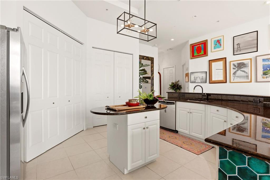 Kitchen with stainless steel appliances, dark stone counters, white cabinetry, a kitchen island, and light tile patterned floors