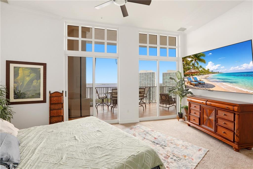Bedroom with light carpet, ceiling fan, access to outside, and a high ceiling