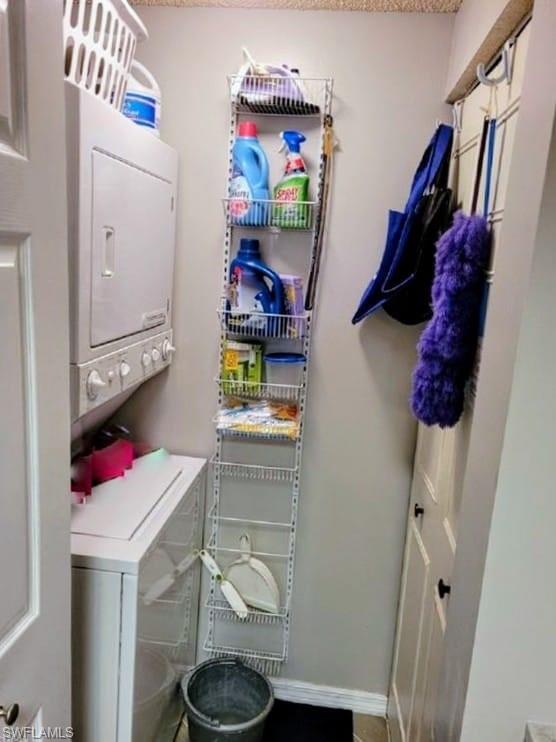 Washroom featuring stacked washer and clothes dryer and baseboards