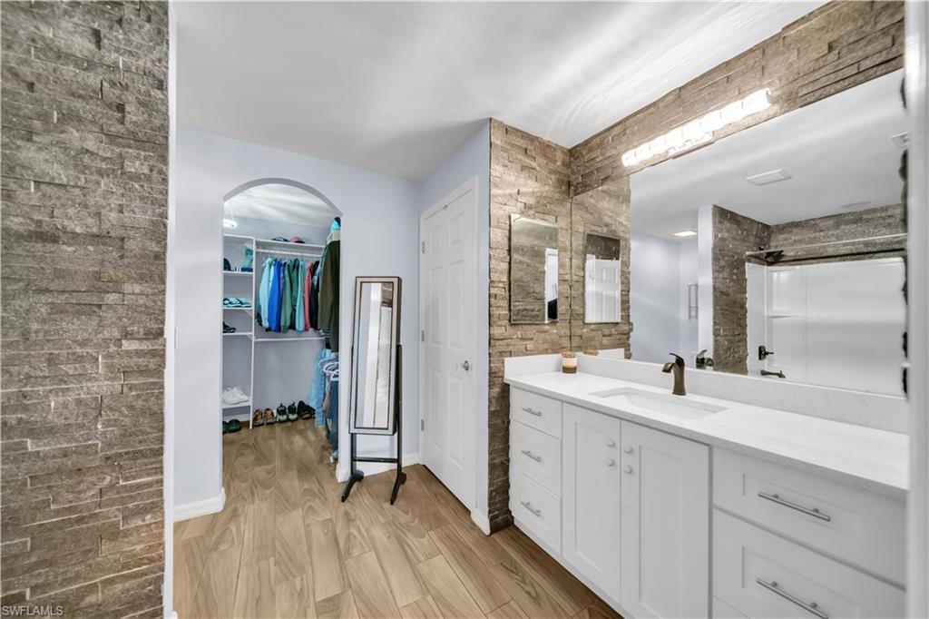 Bathroom with vanity, light wood-type flooring, a walk in closet, and a shower