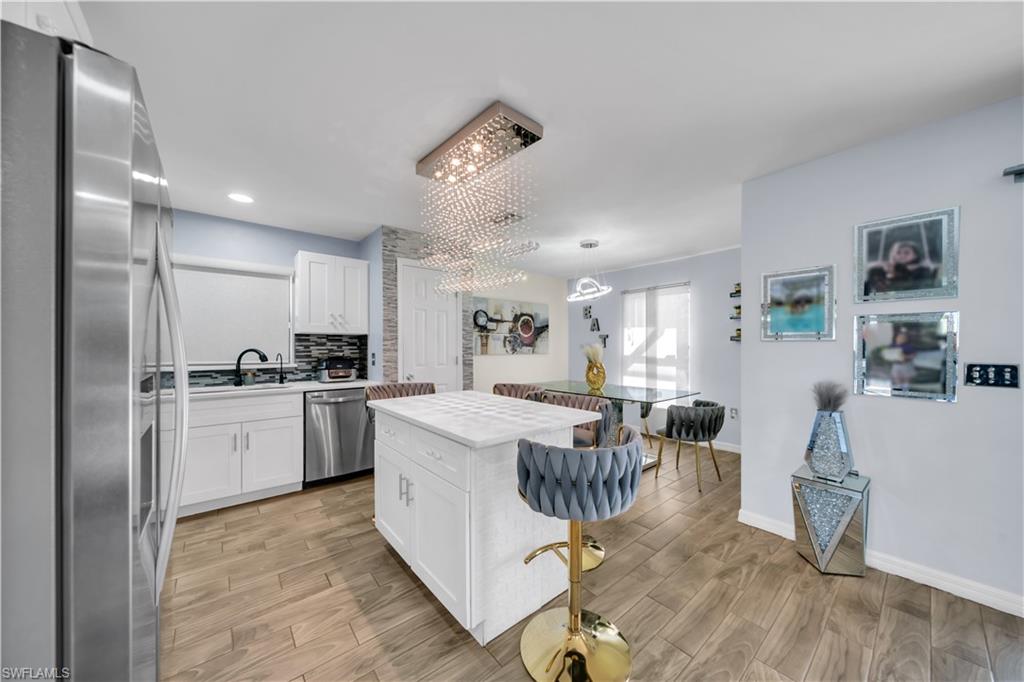 Kitchen featuring stainless steel appliances, wood tiled floors, and white cabinets