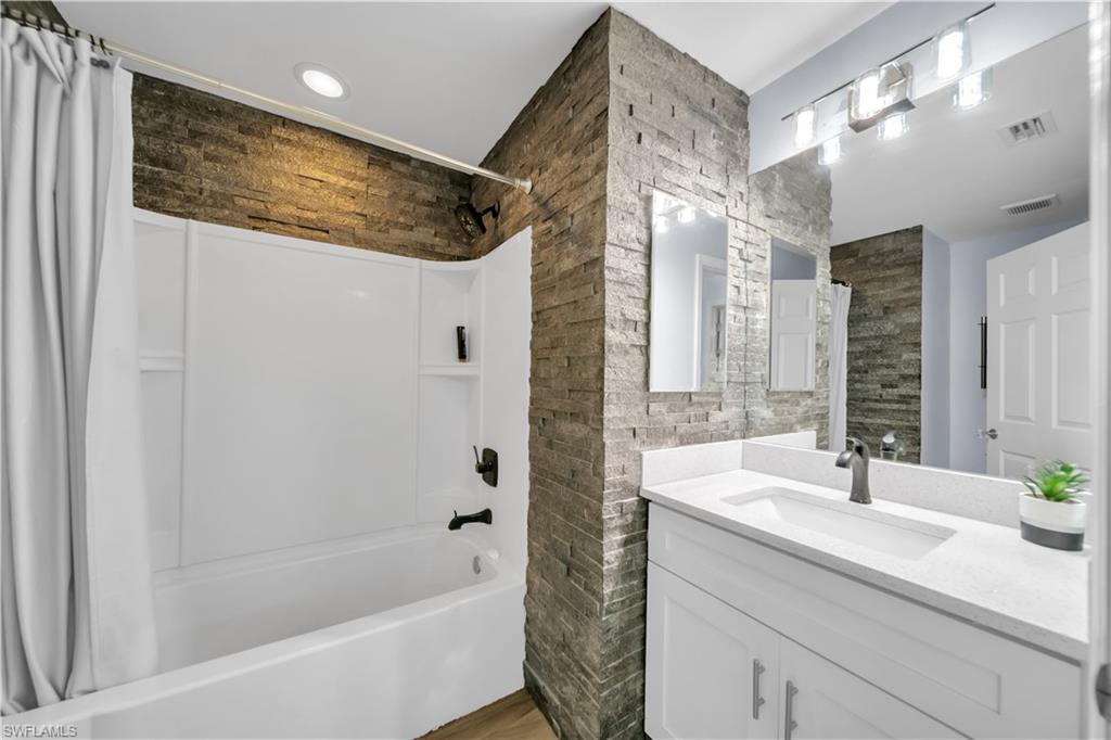 Bathroom featuring vanity, shower / bath combo with shower curtain, and dark wood-style floors