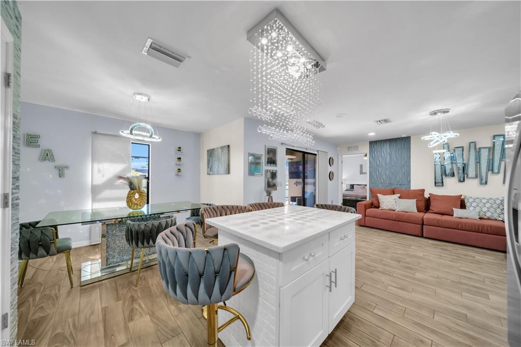 Kitchen featuring a kitchen island, hanging lights, white cabinetry, a breakfast bar area, and open floor plan