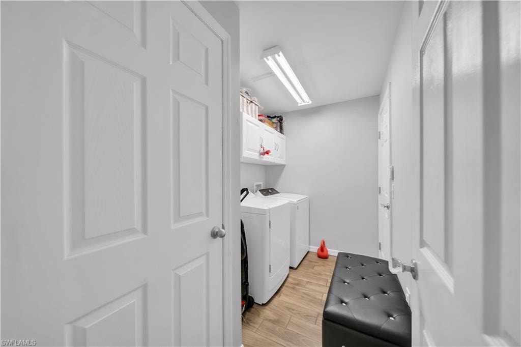 Laundry room featuring light wood-type flooring, washing machine and clothes dryer, and cabinet space