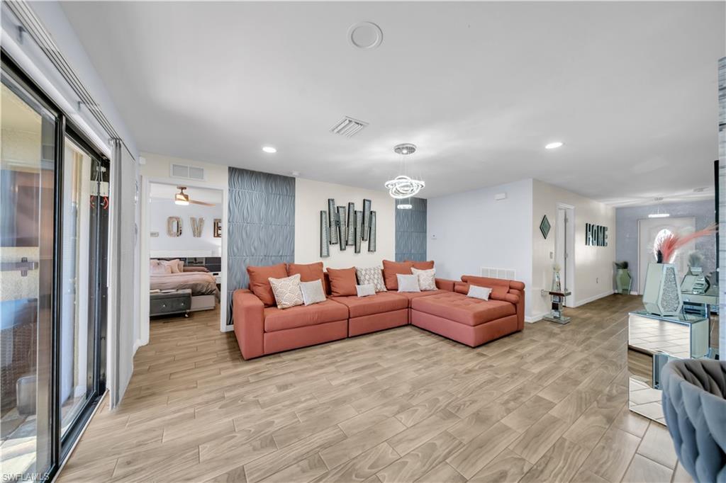 Living room with light wood-style flooring, ceiling fan, and recessed lighting