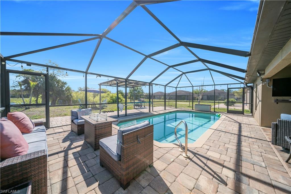 Outdoor pool with a sunroom, a patio, glass enclosure, and an outdoor hangout area