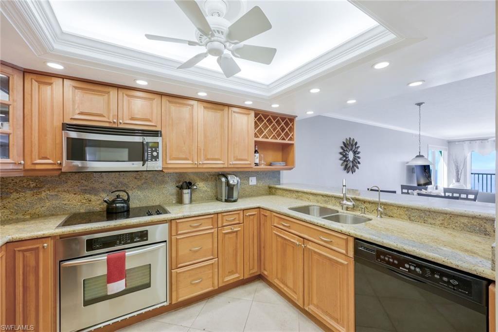 Kitchen featuring ornamental molding, a tray ceiling, black appliances, sink, and tasteful backsplash