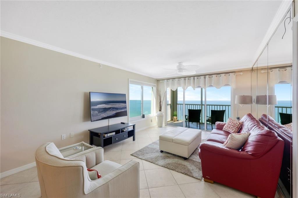 Tiled living room with a water view, ceiling fan, and crown molding