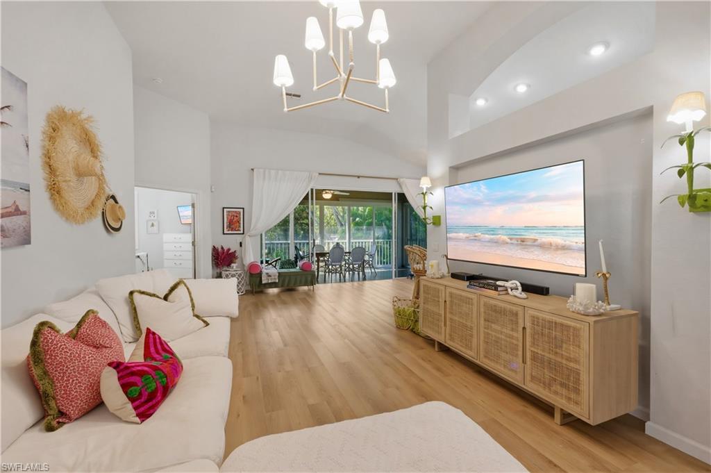 Living area featuring light wood-type flooring, suspended lighting, and vaulted ceiling