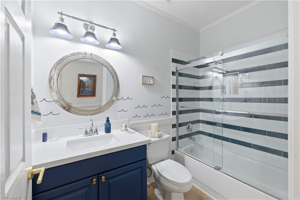 Bathroom featuring vanity, crown molding, and shower / bath combination with glass door