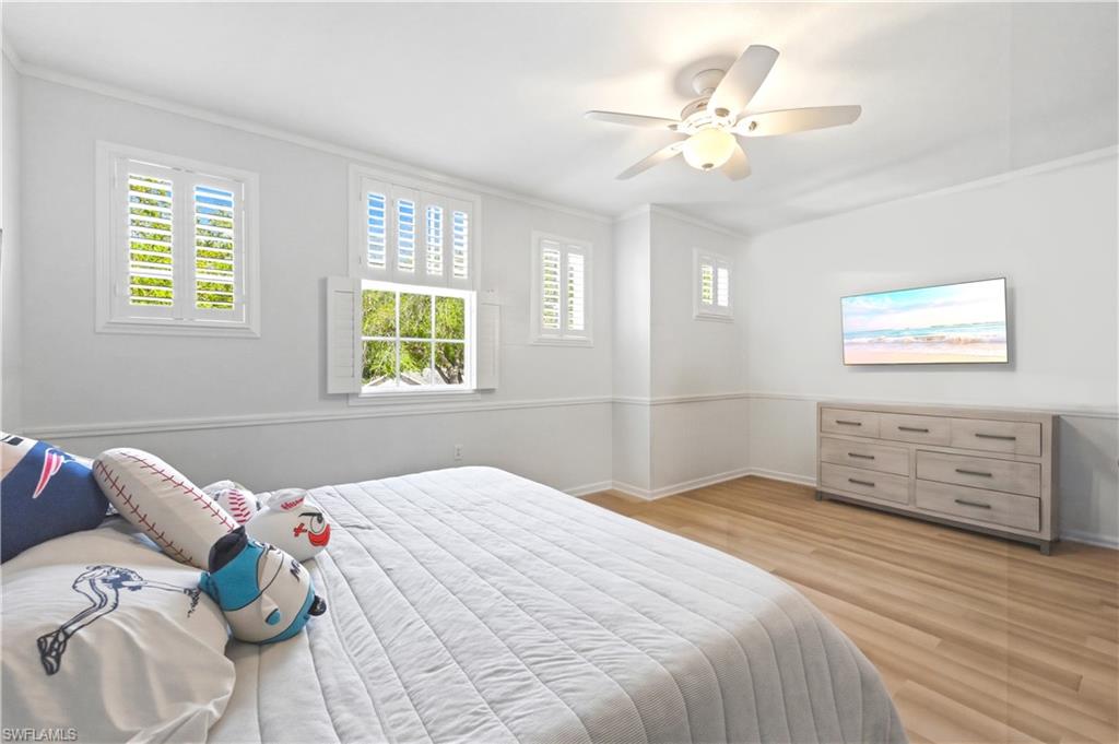 Bedroom featuring ceiling fan, light wood-style flooring, and ornamental molding