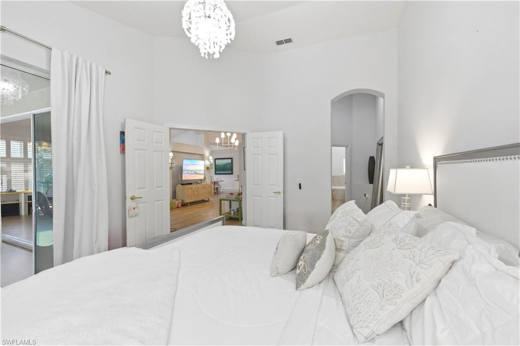 Bedroom with suspended lighting, arched walkways, a high ceiling, a closet, and connected bathroom