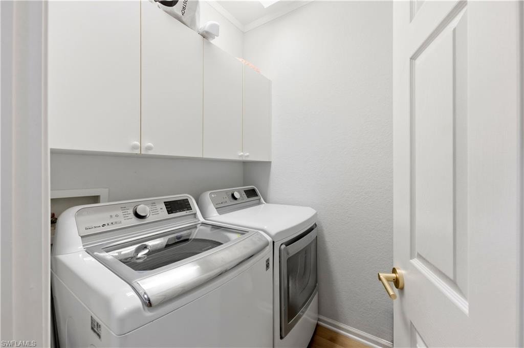 Laundry room featuring a textured wall, cabinet space, and washer and clothes dryer