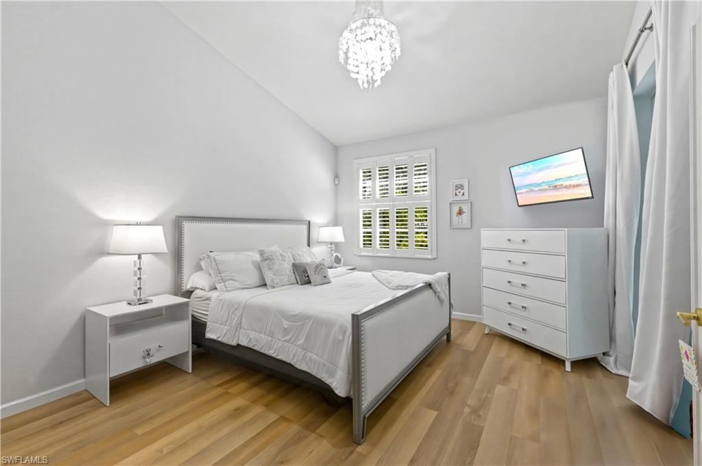 Bedroom with lofted ceiling, light wood-style flooring, and suspended lighting