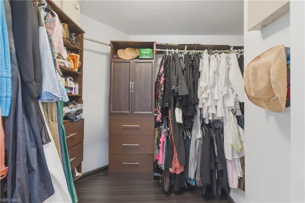Walk in closet with dark wood-style flooring