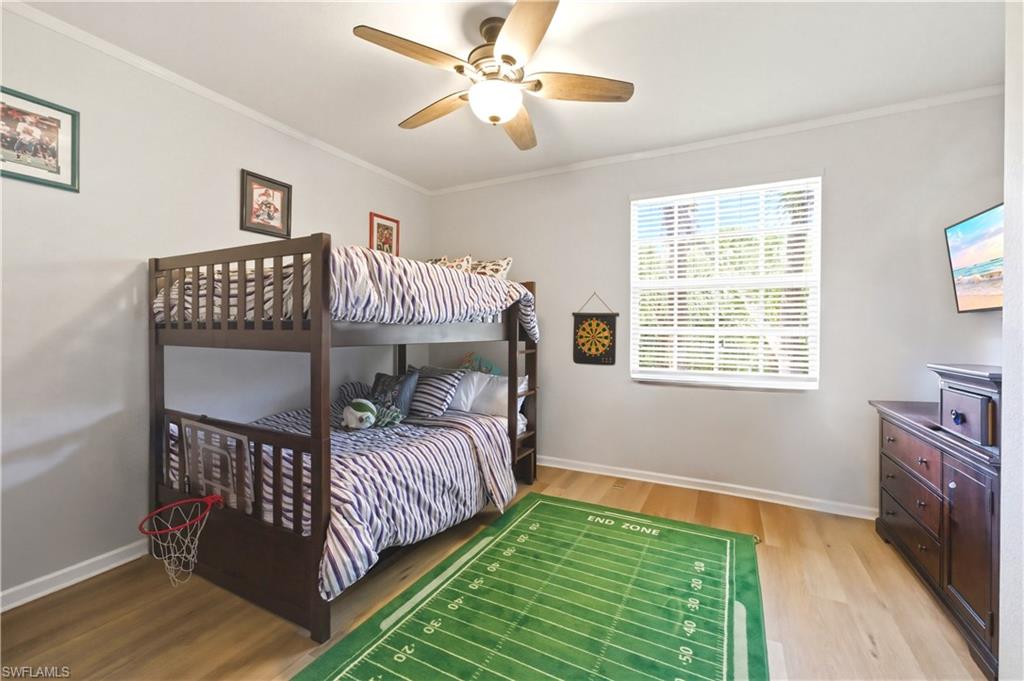 Bedroom featuring ornamental molding, light wood-style flooring, and a ceiling fan